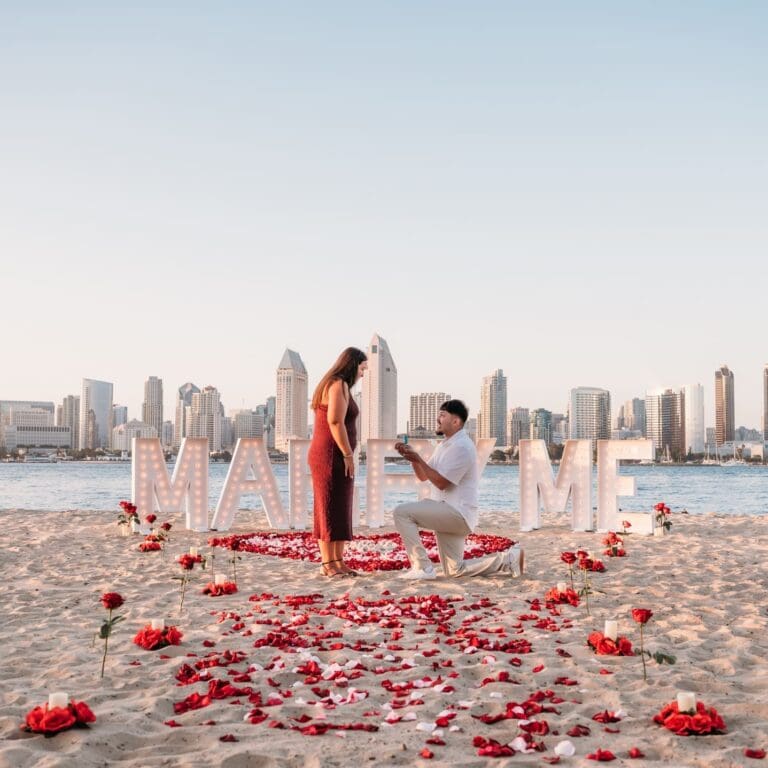 MARRY ME marquee letters with rose petals for a proposal at Coronado Beach overlooking the San Diego skyline